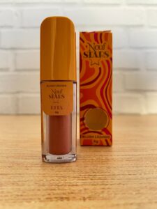 Nouf blush líquido da linha Stars na cor Rita, com embalagem quadrada transparente, tampa laranja vibrante e caixinha com design psicodélico em laranja e rosa, contendo 6g.