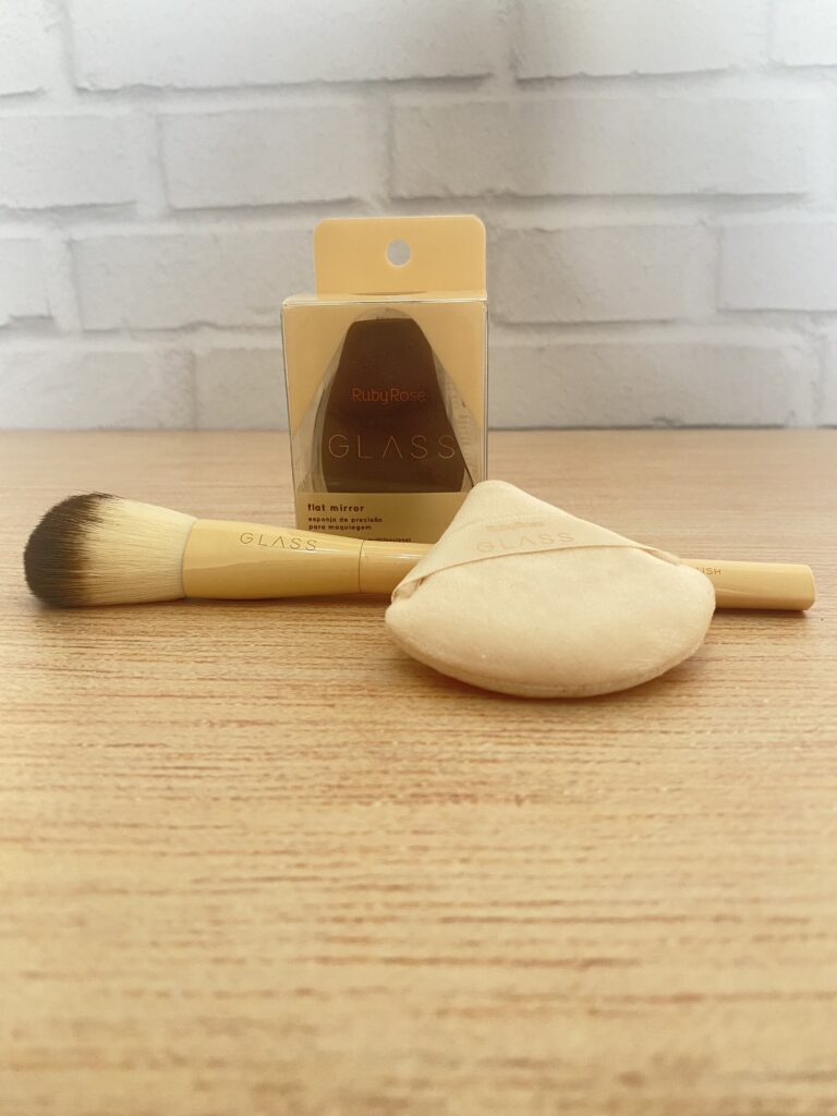 Kit de maquiagem Ruby Rose Glass composto por pincel bege com cerdas macias, esponja chanfrada aveludada e aplicador de pó em formato triangular.