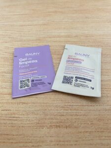 Bauny apresenta dois sachês: um gel de limpeza facial roxo com niacinamida e outro esfoliante bege com esferas vegetais e ácido hialurônico. Ambos são veganos e vêm em embalagens de 1g.