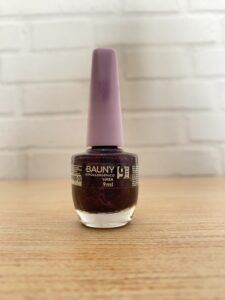 Bauny esmalte hipoalergênico com glitter roxo, frasco de vidro transparente com tampa lilás. Contém 9ml e acabamento brilhante.