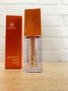 Mari Maria MakeUp gloss labial Glassy Lips com brilho perolado, embalagem retangular com tampa laranja e texto dourado. Acompanha caixa da mesma cor com nome em dourado.