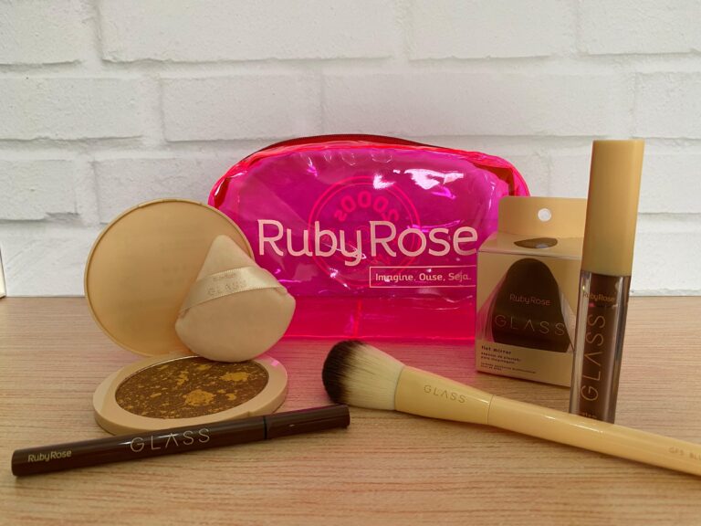 Ruby Rose destaca a linha Glass na Beauty Show 2025 com nécessaire rosa vibrante, pó compacto marmorizado, esponja de acabamento aveludado, pincel para blush, gloss labial e caneta para sobrancelhas