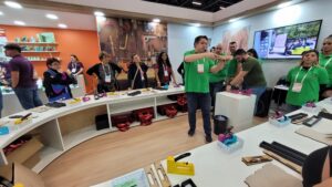 Rocama realiza oficina prática na Mega Artesanal 2025 com público testando grampeadores e montando peças em MDF.