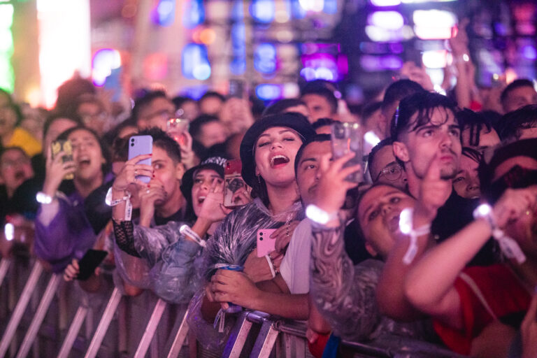 The Town emociona o público com apresentação no palco Skyline; fãs eufóricos na grade registram o show com celulares, usando capas de chuva e pulseiras de LED brilhantes.
