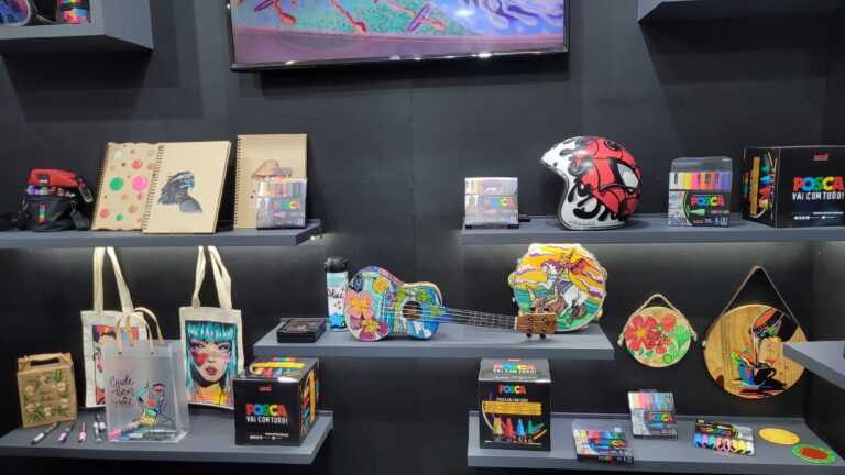 Posca apresenta uma vitrine criativa na Mega Artesanal 2025 com instrumentos musicais, capacetes, cadernos e bolsas decoradas, mostrando a aplicação artística dos marcadores em papel, tecido, plástico e madeira.