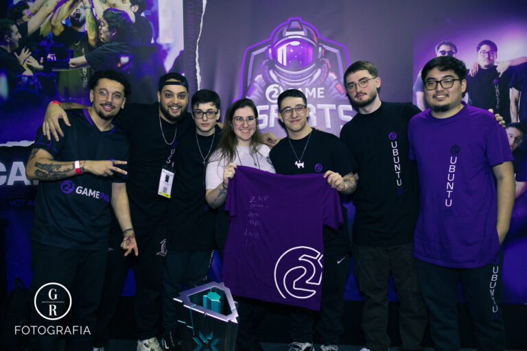 BGS 2023: equipe da Ubuntu Esports posa ao lado de fãs com camiseta autografada durante ativação da GameXP, em um estande iluminado com temática gamer e atmosfera descontraída.