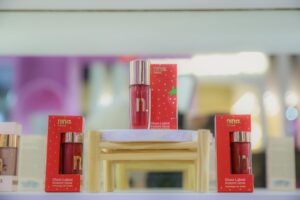 Gloss Morango do Amor da Nina Makeup exposto na Beauty Fair 2025 com embalagem vermelha inspirada no doce tradicional.