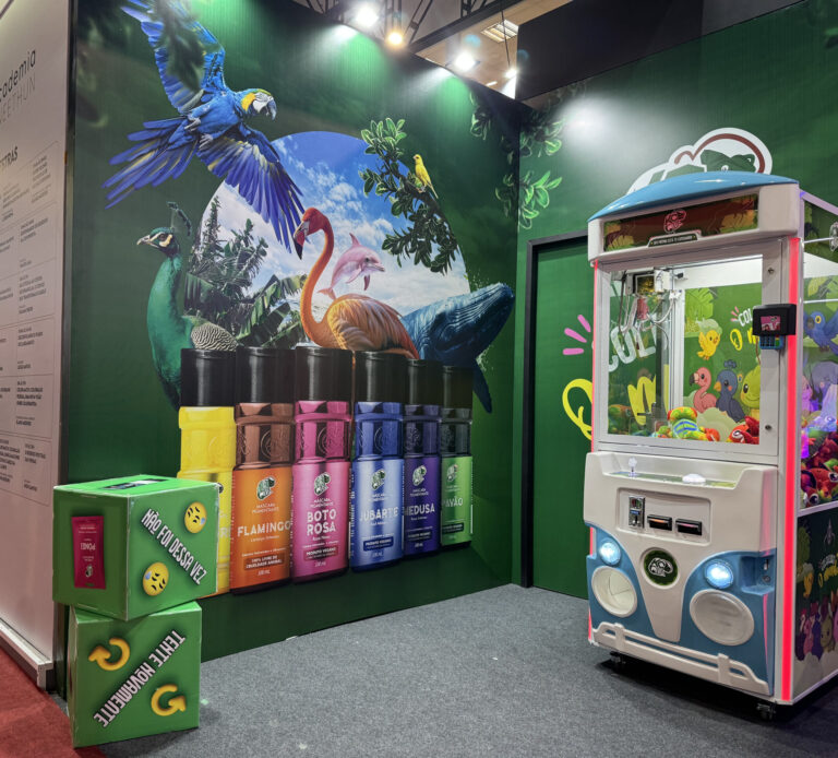 Área de ativações da Kamaleao na Beauty Fair com a máquina de brindes e parede ilustrada com animais tropicais e linhas coloridas de produtos.