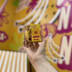 Produto da linha Banana da Melu exibido no estande durante a Beauty Fair 2025.