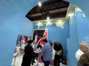 Espaço interno do estande Poran na Beauty Fair 2025, com clientes e parceiros reunidos em mesas de atendimento.