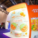 Fachada temática da linha Pistachill da Melu, inspirada em sobremesas, na Beauty Fair 2025.