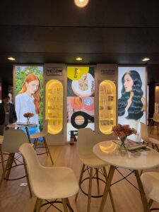 Painéis da Alfaparf e Yellow Professional no estande da Beauty Fair 2025, com displays de produtos e mesas de atendimento ao público.