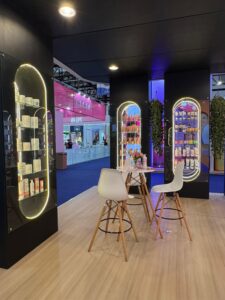 Área interna do estande da Alfaparf na Beauty Fair 2025, com vitrines iluminadas, produtos expostos e mesas para interação com visitantes.
