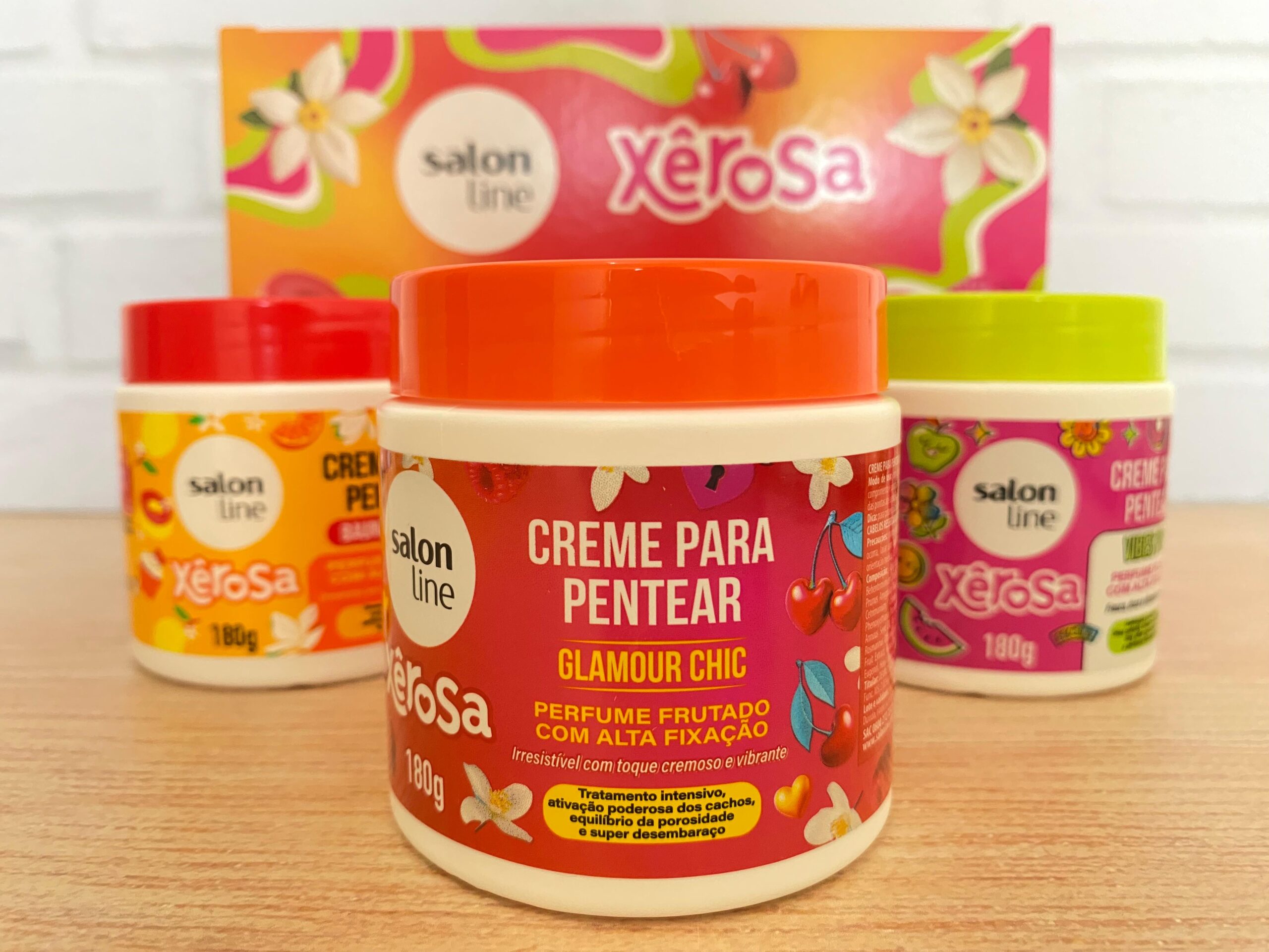Linha Xêrosa da Salon Line com cremes para pentear Glamour Chic, Baunilha Doce e Vibes Pop exibidos em destaque sobre mesa de madeira.