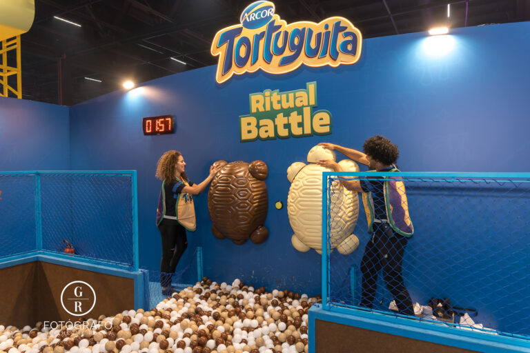 Público participa da atividade Ritual Battle da Tortuguita no estande da Arcor durante a BGS 2025, montando peças gigantes em formato de tartaruga dentro de uma piscina de bolinhas.