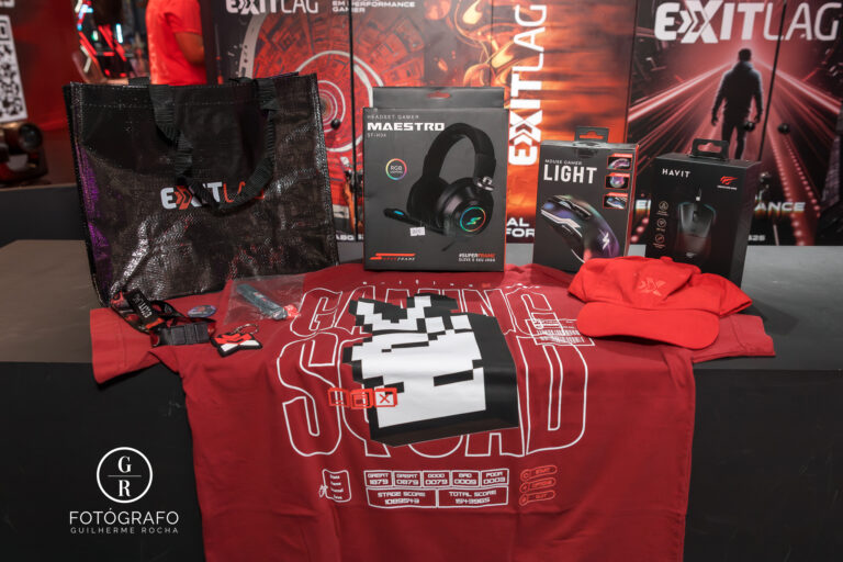 Kit de brindes da ExitLag na BGS 2025 com camiseta, boné, mouse gamer, headset e bolsa personalizada em exposição no estande.