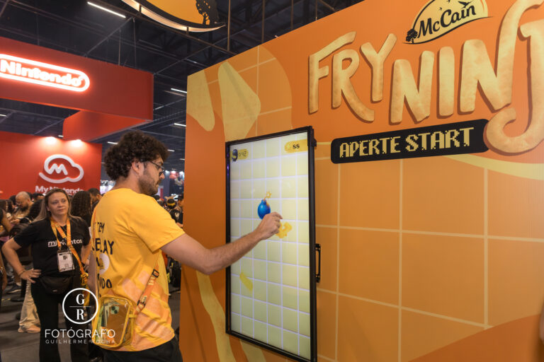 Participante joga o mini-game Fry Ninja no estande da McCain durante a BGS 2025, cortando batatas virtuais em uma tela interativa para ganhar brindes.