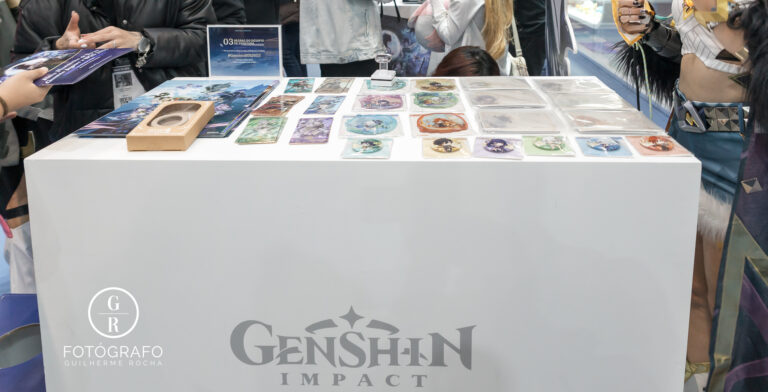 Balcão de ativações de Genshin Impact na BGS 2025 com brindes colecionáveis, como cards e adesivos, distribuídos aos participantes das atividades.