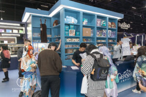 Loja oficial de Genshin Impact na BGS 2025, com prateleiras cheias de produtos colecionáveis, figures e acessórios, atraindo fãs e cosplayers durante o evento.