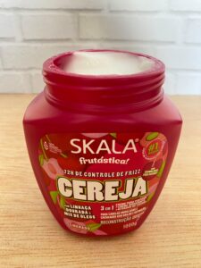 Máscara Skala Frutástica Cereja aberta, mostrando a textura cremosa do produto de reconstrução capilar e controle de frizz.