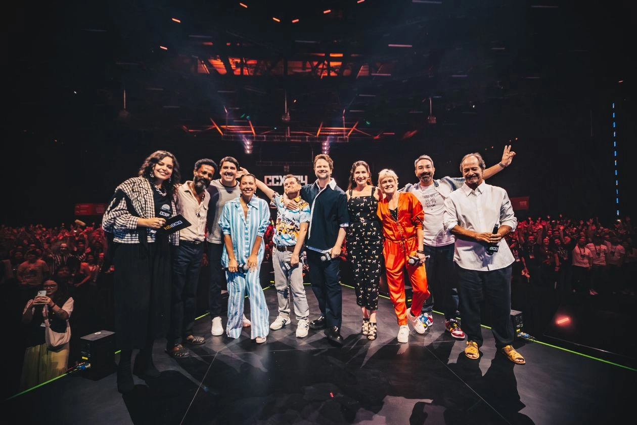 Elenco de O Auto da Compadecida 2 posa no palco do Palco Thunder by Claro tv+ durante a CCXP24, celebrando o painel e a pré-estreia exclusiva do filme diante de um público entusiasmado.