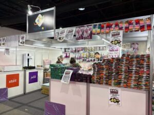 Estande de materiais de artesanato Patch na Criativa, com linhas, tesouras e kits organizados sobre bancadas.