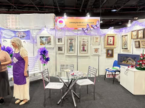 Estande completo da Exposição de Arte Francesa na Criativa Campinas, com mesas, quadros tridimensionais e artistas conversando no espaço.