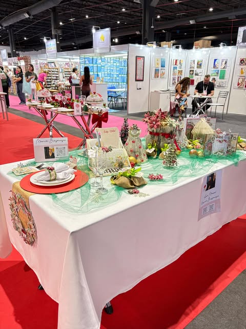 Mesa decorada com tema natalino na Criativa Campinas, com enfeites artesanais, arranjos coloridos e detalhes festivos sobre toalha branca.