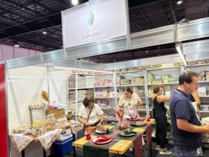 Estande do Atelier Café Arte na Criativa, mostrando jogos de mesa decorados, toalhas e produtos artesanais organizados.