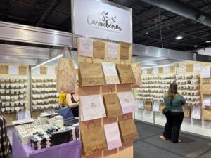 Estande Carimbeiros na Criativa, com expositores cheios de carimbos organizados e sacolas artesanais penduradas.