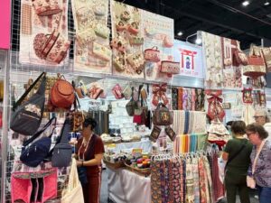 Estande Ton com Ton na Criativa, com bolsas, tecidos, utilitários e peças artesanais expostas em painéis e prateleiras.