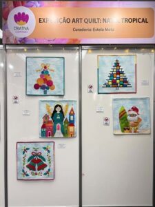 Painel da Exposição Art Quilt: Natal Tropical na Criativa Campinas, com quilts criativos representando temas natalinos tropicais.