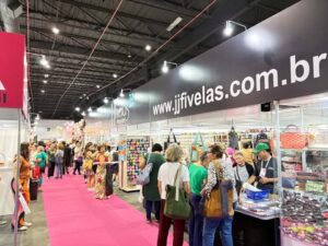 Corredor movimentado da Criativa com o estande da JJ Fivelas, apresentando acessórios e materiais para artesanato.