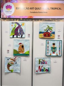 Painel da Exposição Art Quilt: Natal Tropical na Criativa Campinas, com quilts criativos representando temas natalinos tropicais.