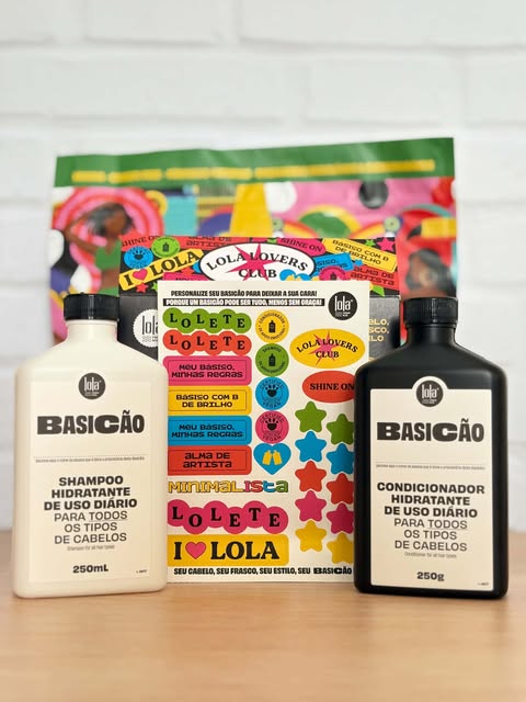 Frascos do shampoo e condicionador Lola Basicão ao lado da cartela de adesivos, todos dispostos em frente ao fundo colorido da marca.