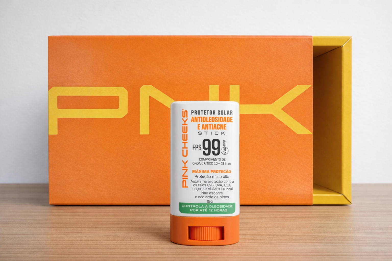 Protetor solar stick FPS 99 da Pink Cheeks antioleosidade e antiacne, em destaque com embalagem branca e laranja, posicionado à frente da caixa do produto.