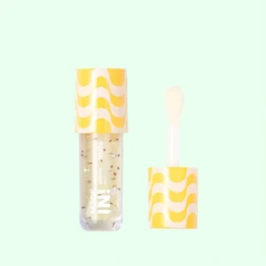 Lip oil melu Made In banana com aplicador e partículas douradas, embalagem amarela vibrante inspirada em doce de banana.