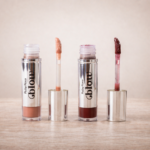 Gloss labial da linha Blow da ruby rose com dois tons e aplicadores abertos sobre superfície de madeira com fundo neutro.