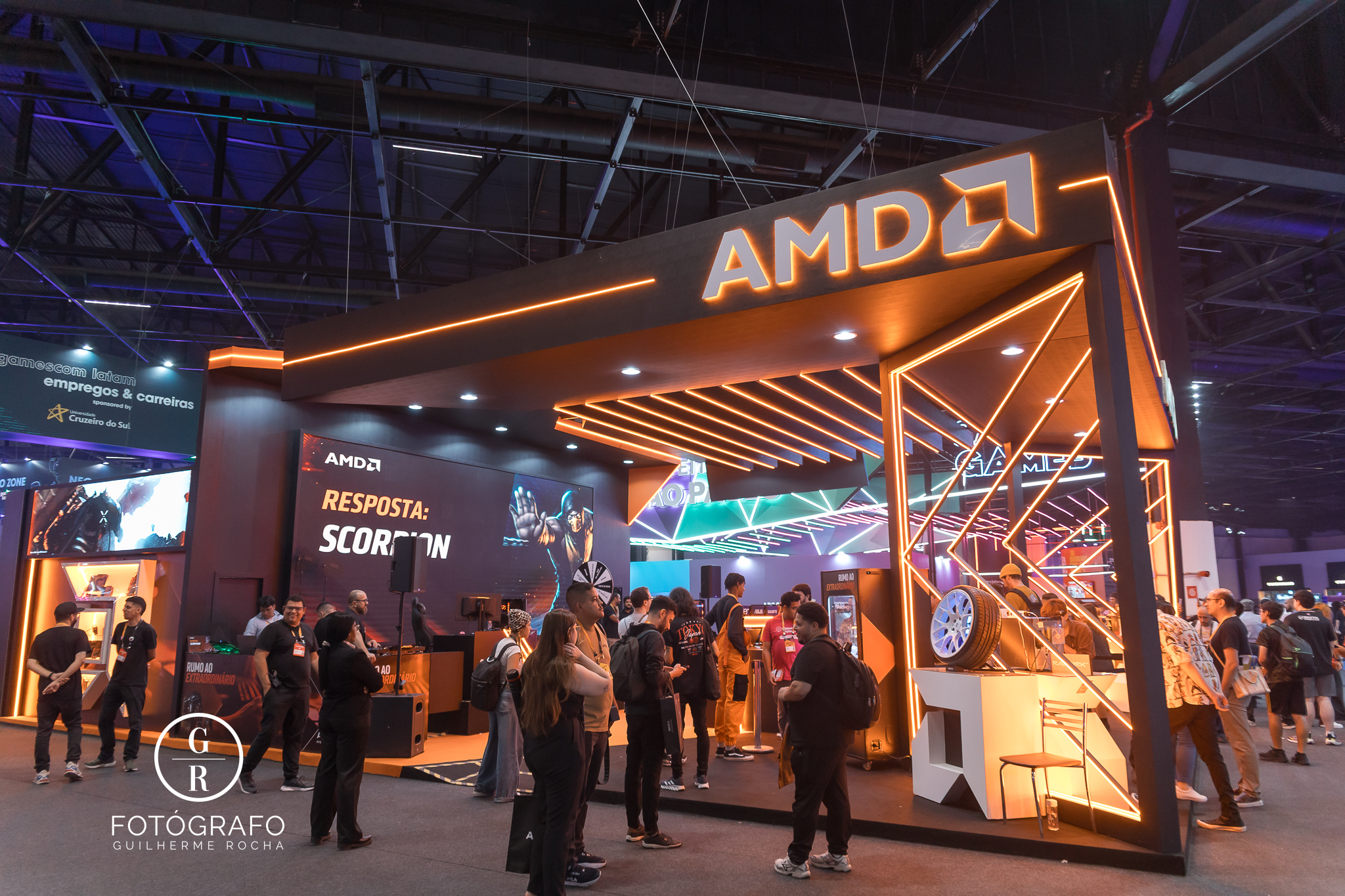 Visão geral do estande da AMD na Gamescom 2026 com iluminação em LED e grande movimentação de visitantes