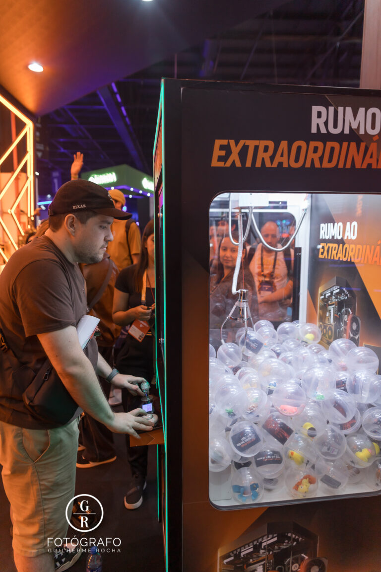 Visitante participa da máquina de garra no estande da AMD na Gamescom 2026 tentando pegar brindes
