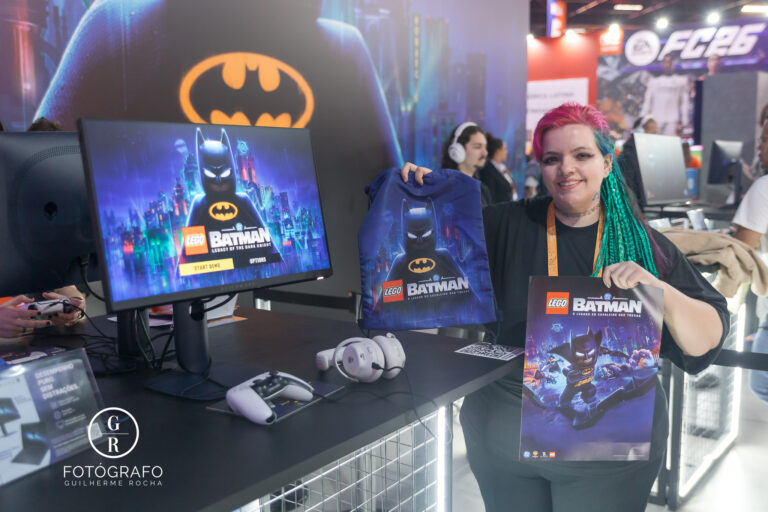 Estande da Warner Bros na gamescom latam com demonstração de LEGO Batman, visitante segurando ecobag e pôster do jogo.