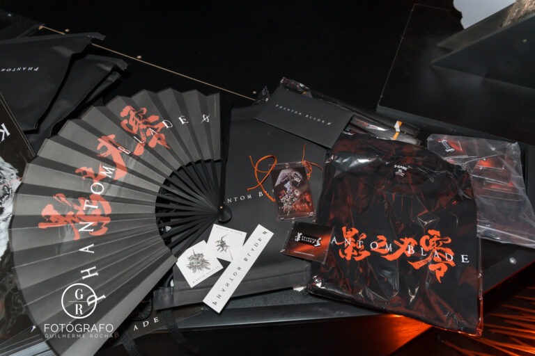 Kit de brindes de Phantom Blade Zero com camiseta, leque, cards e itens colecionáveis expostos no estande.