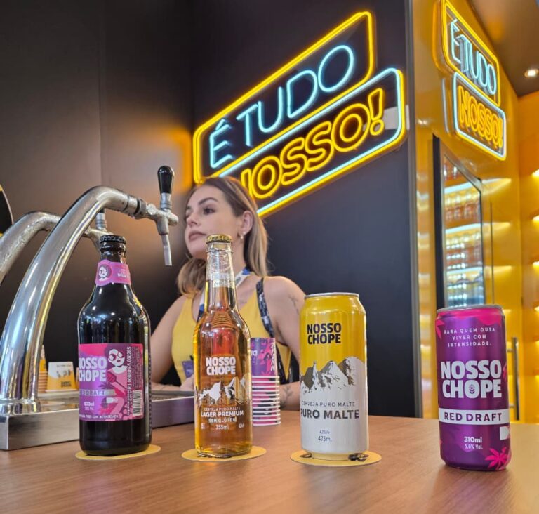 Produtos da Nosso Chope expostos no balcão da APAS Show 2026 com chope de vinho, lager premium sem glúten e cerveja puro malte.