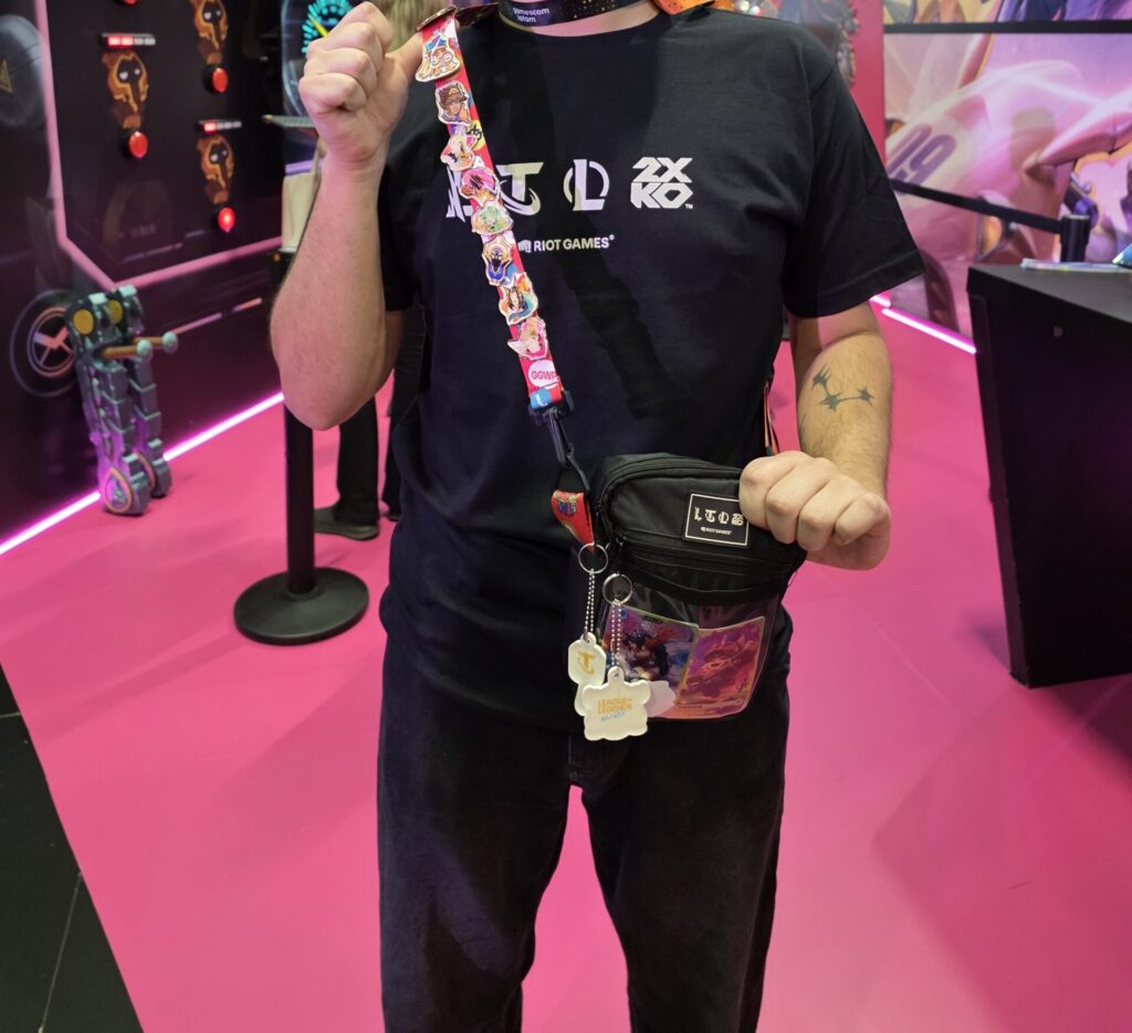 Visitante no estande da Riot Games exibindo pins e brindes conquistados após completar as ativações interativas.