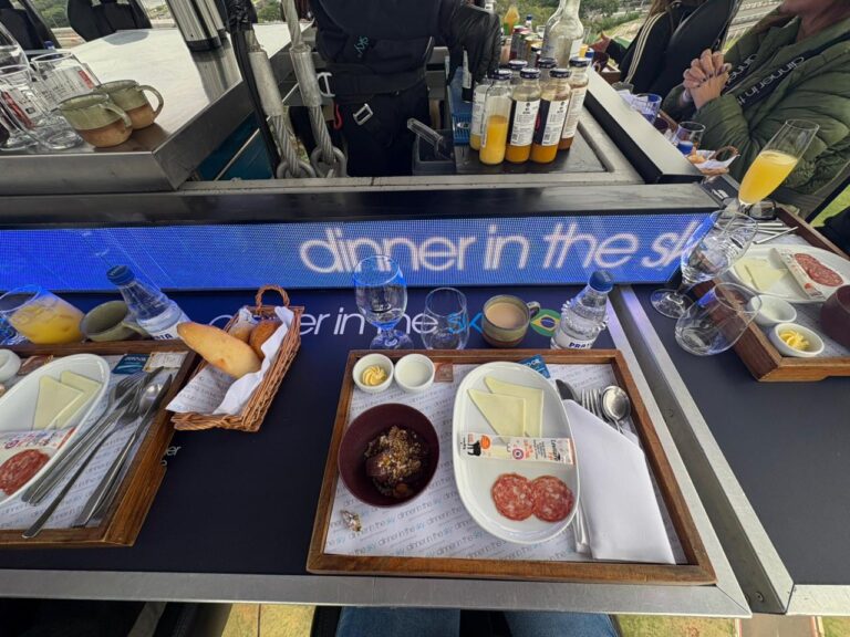Mesa do café da manhã do Dinner in the Sky apresenta pães, frios, bebidas e serviço premium suspenso a 50 metros.