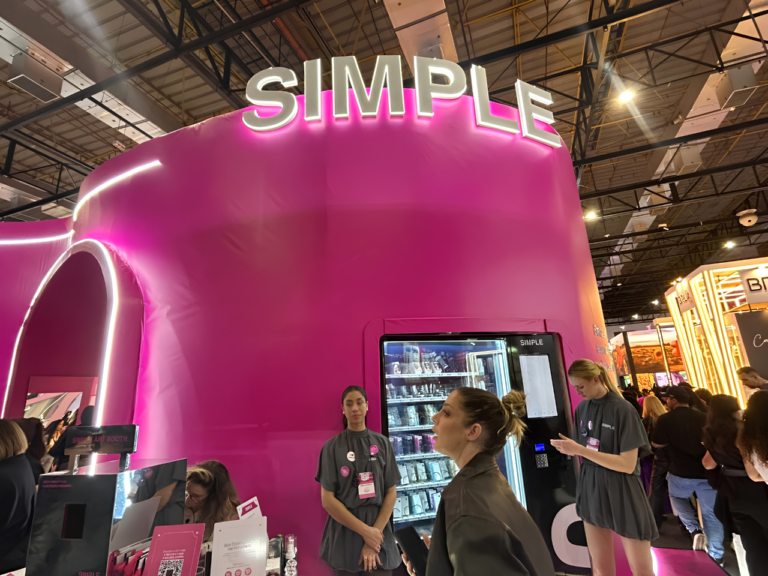 Detalhe do estande da Simple Organic na Beauty Show 2026, com identidade visual em tons de rosa, estrutura inspirada na letra "S" e espaço dedicado à apresentação dos produtos de beleza limpa da marca.