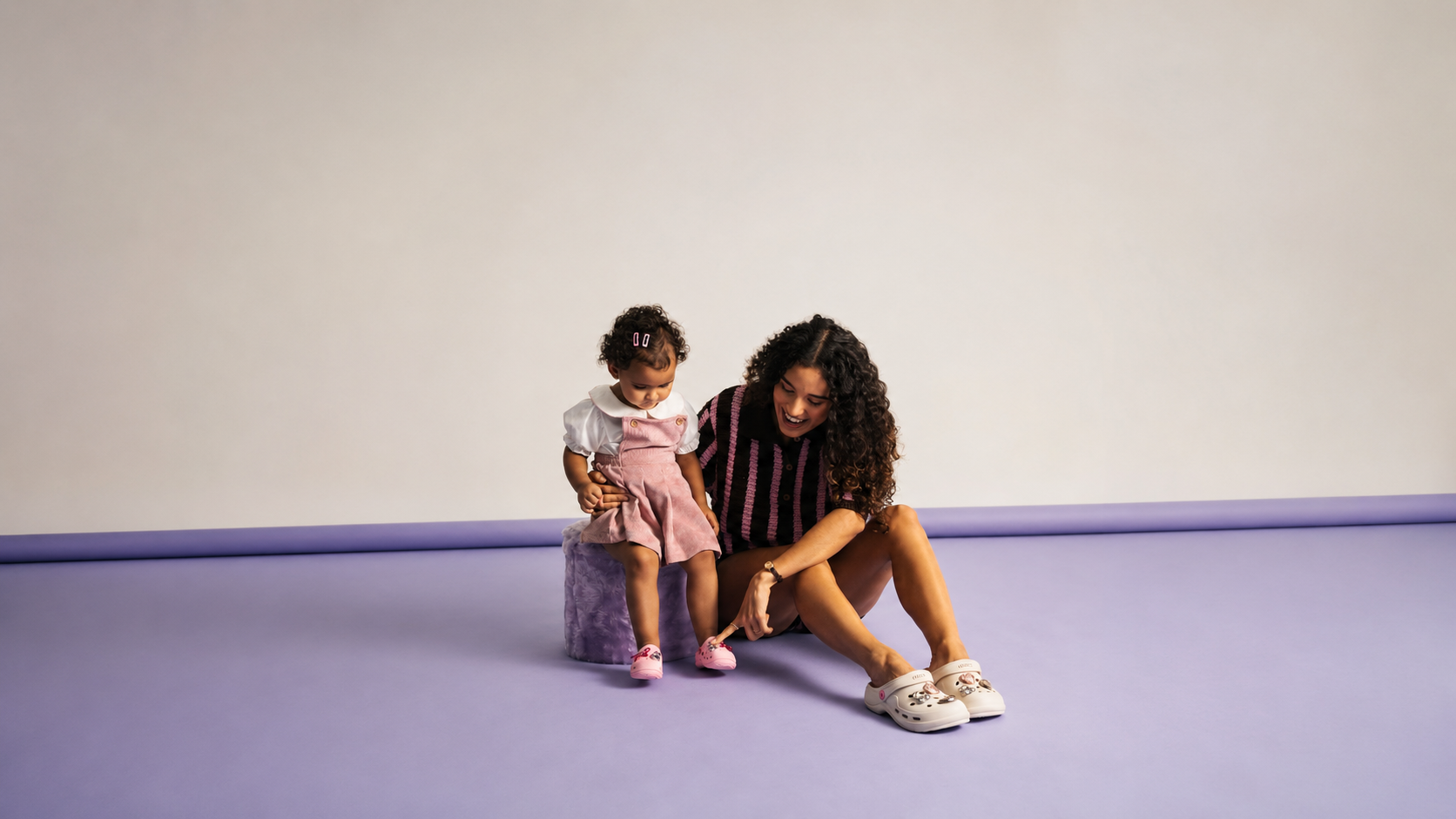 Mãe e filha usando calçados Zaxy em ensaio minimalista com fundo lilás, destacando conforto, estilo e modelos customizáveis da coleção de Dia das Mães da Zaxy.