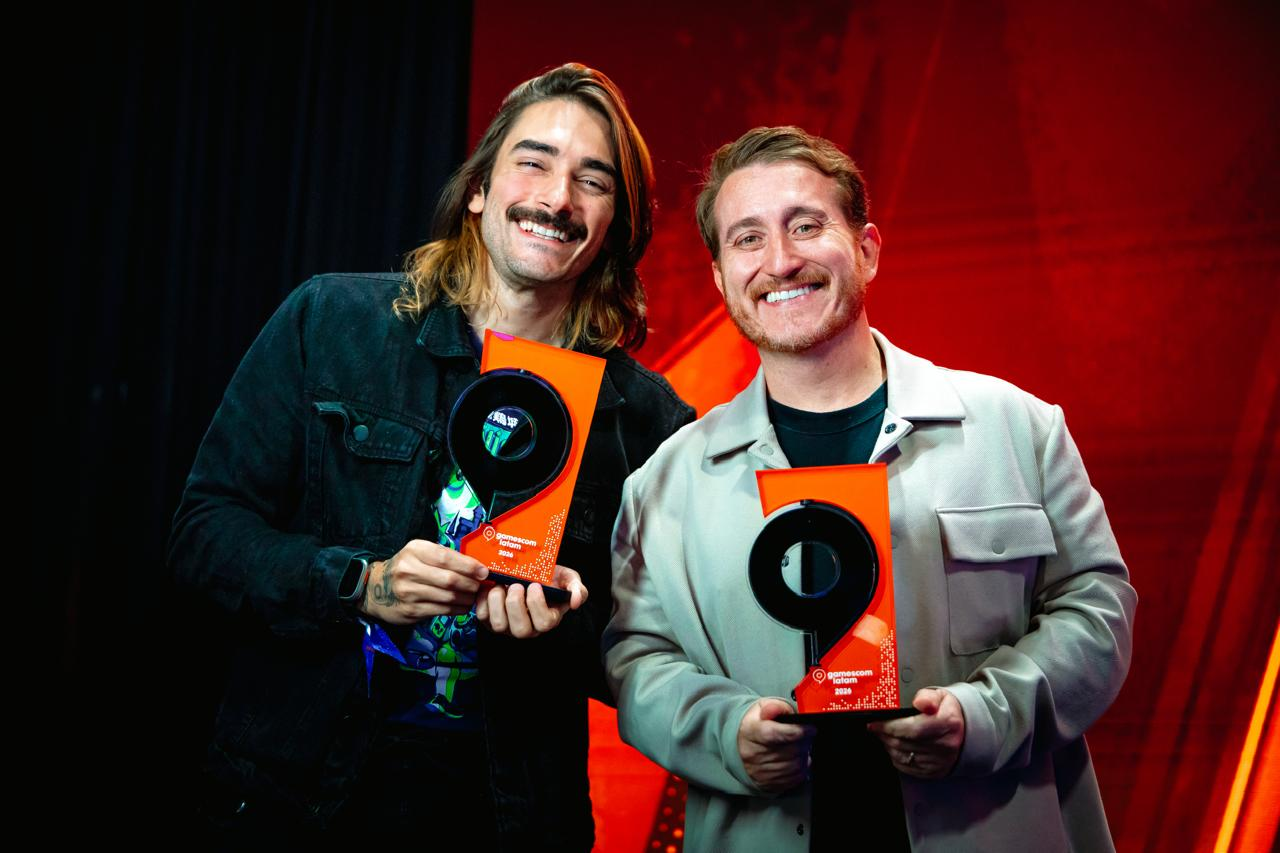Representantes da Riot Games exibem troféus conquistados durante a gamescom latam awards 2026, destacando os prêmios recebidos por 2XKO e Wild Rift em um palco iluminado com tons vermelhos.