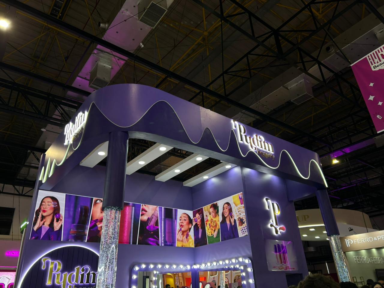 Pudim Beauty apresenta estande temático na Beauty Show 2026 com identidade visual inspirada em sobremesas, iluminação em tons de roxo e espaço dedicado à experiência dos visitantes.
