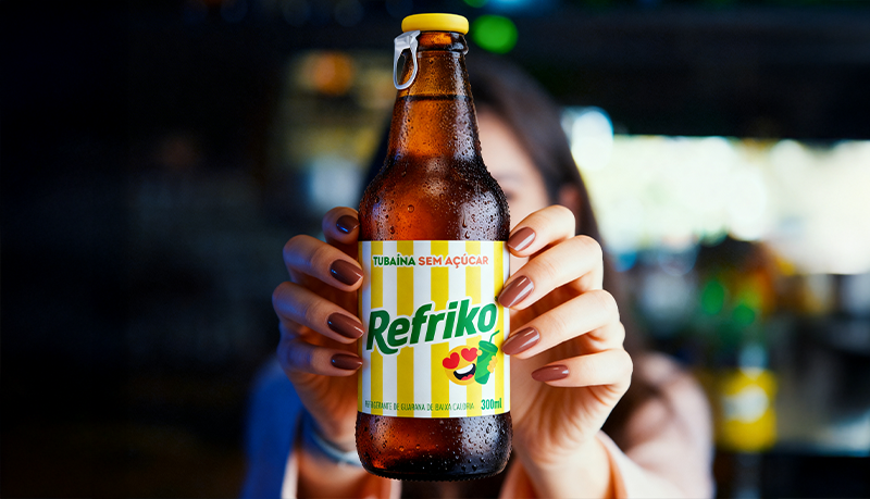 Garrafa da Refriko Tubaína Sem Açúcar sendo segurada em destaque durante ação promocional na Apas Show 2026, reforçando os lançamentos do Grupo RFK no evento.